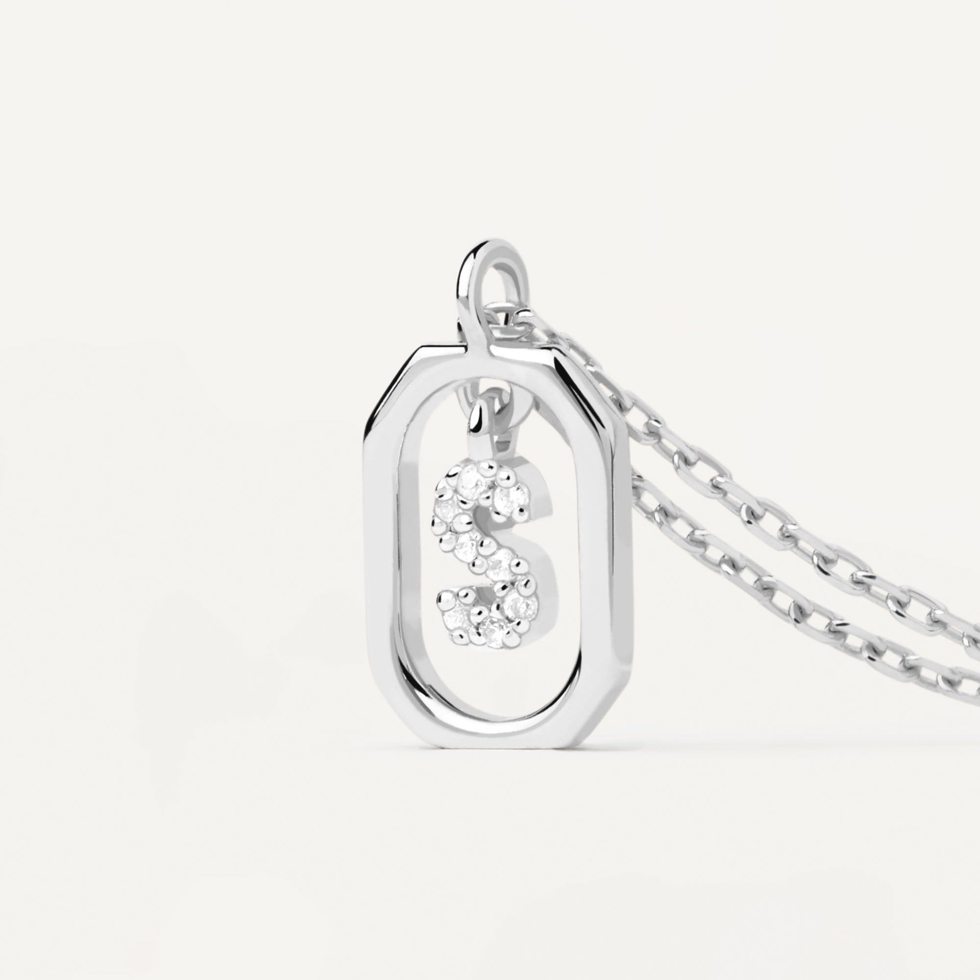 Die PDPaola Halskette - The Mini Letter S von PDPaola besteht aus einem achteckigen Anhänger aus 925er Sterlingsilber mit einem funkelnden, mit Zirkonia besetzten Buchstaben S in der Mitte.