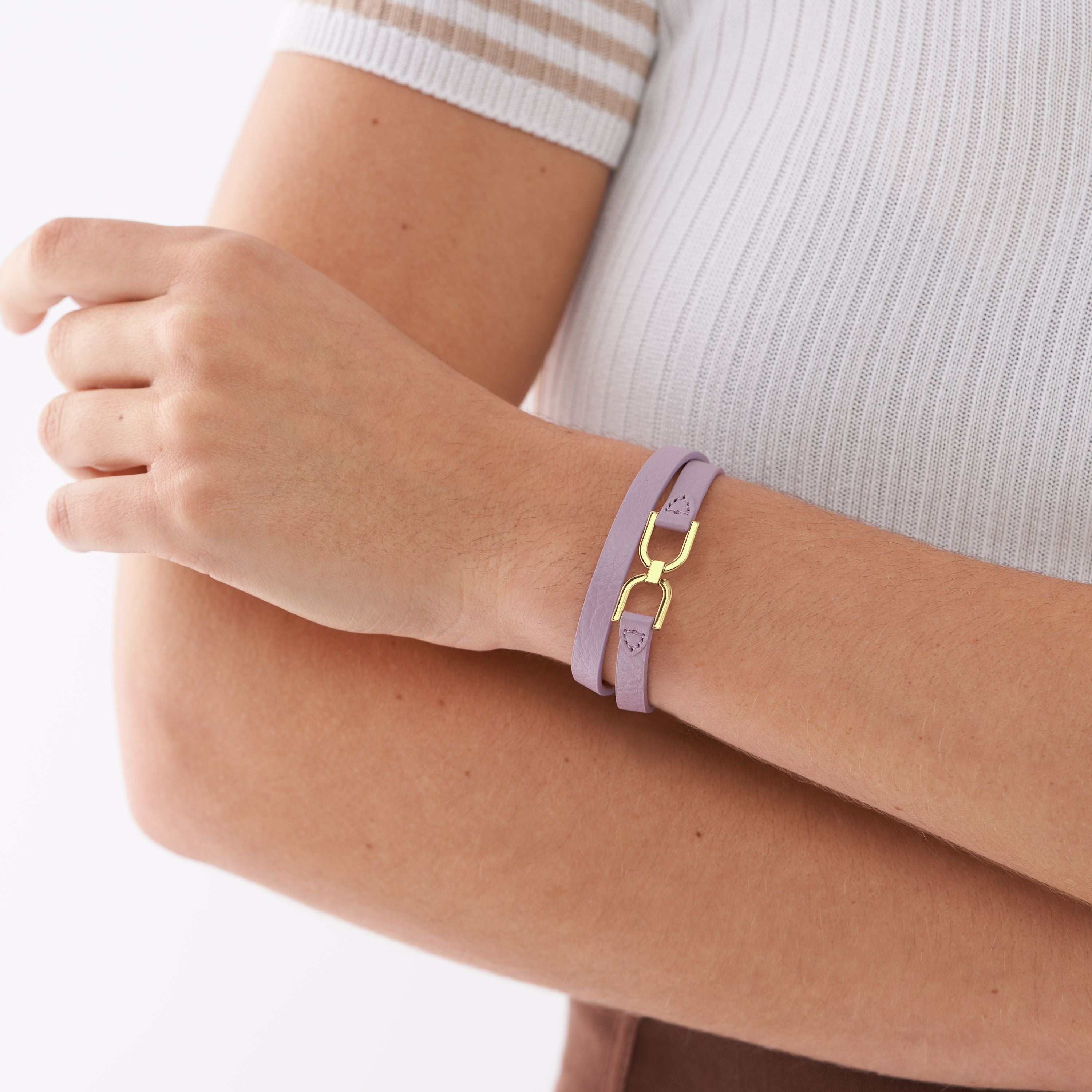 Eine Person trägt das Fossil Armband - Heritage D-Link Lavendel mit goldener Schließe am Handgelenk - eine stilvolle Ergänzung für jede Schmuckkollektion.