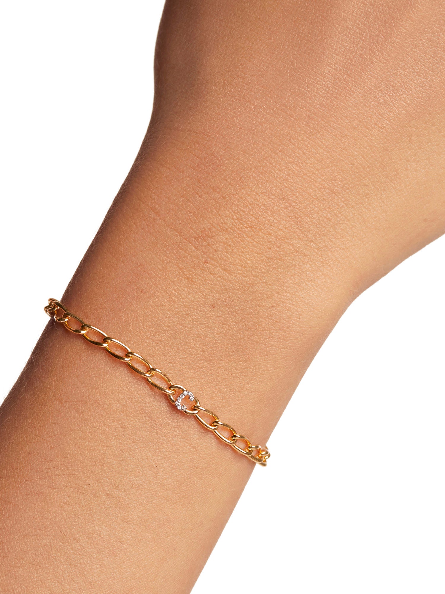 Ein PDPaola Armband - Gliederband Buchstabe C Goldkettenarmband mit einem kleinen runden Zirkonia-Edelstein wird am Handgelenk getragen.