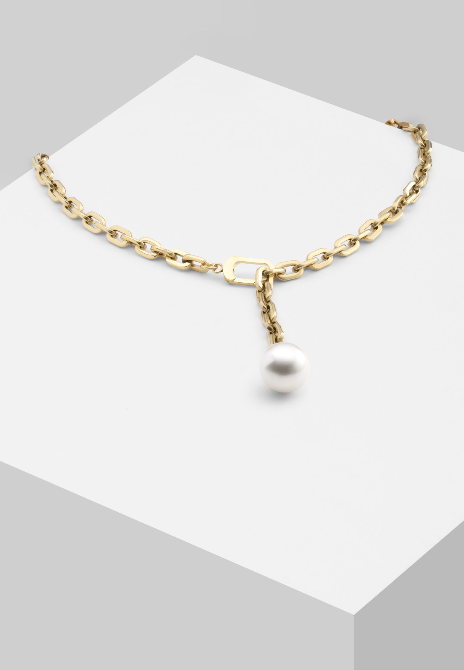 Die LIEBESKIND BERLIN Halskette - The Short Pearl von Liebeskind Berlin präsentiert eine einzelne weiße Perle in moderner Goldoptik aus Edelstahl, elegant auf weißem Podest - die perfekte zarte Perlenkette für stilvolle Akzente.