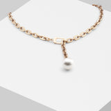 Die LIEBESKIND BERLIN Halskette - The ShortPearl von Liebeskind Berlin ist eine Goldkette im Gliederketten-Stil mit einem großen weißen Perlenanhänger, variabel verstellbar, dargestellt auf einer weißen geometrischen Fläche.