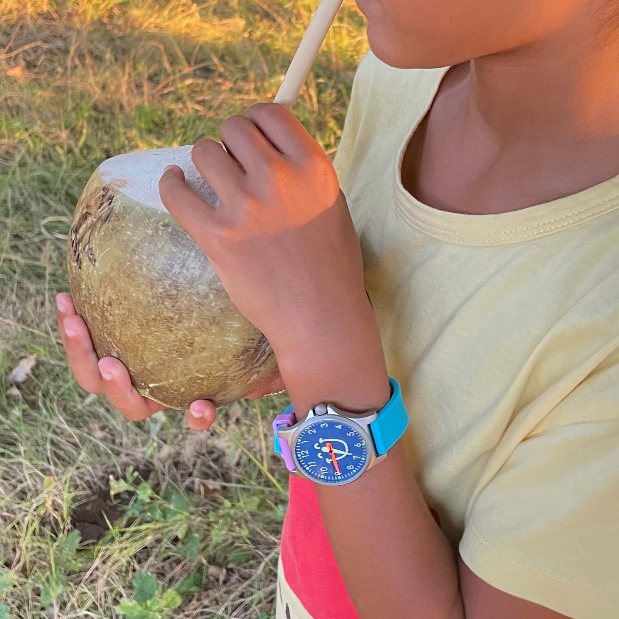 Cool Time Kids Armbanduhr mit lila Zifferblatt mit Smiley-Motiv, silbernem Gehäuse und lila-blauem Silikongehäuse; Tragebild
