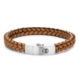 Das Rebel & Rose Armband - The Braided Leather ist ein hellbraunes, geflochtenes Lederarmband mit einem silbernen, eingravierten Logo-Verschluss, Teil der Absolutely Leather Lederkollektion von Rebel & Rose, abgebildet auf weißem Hintergrund.