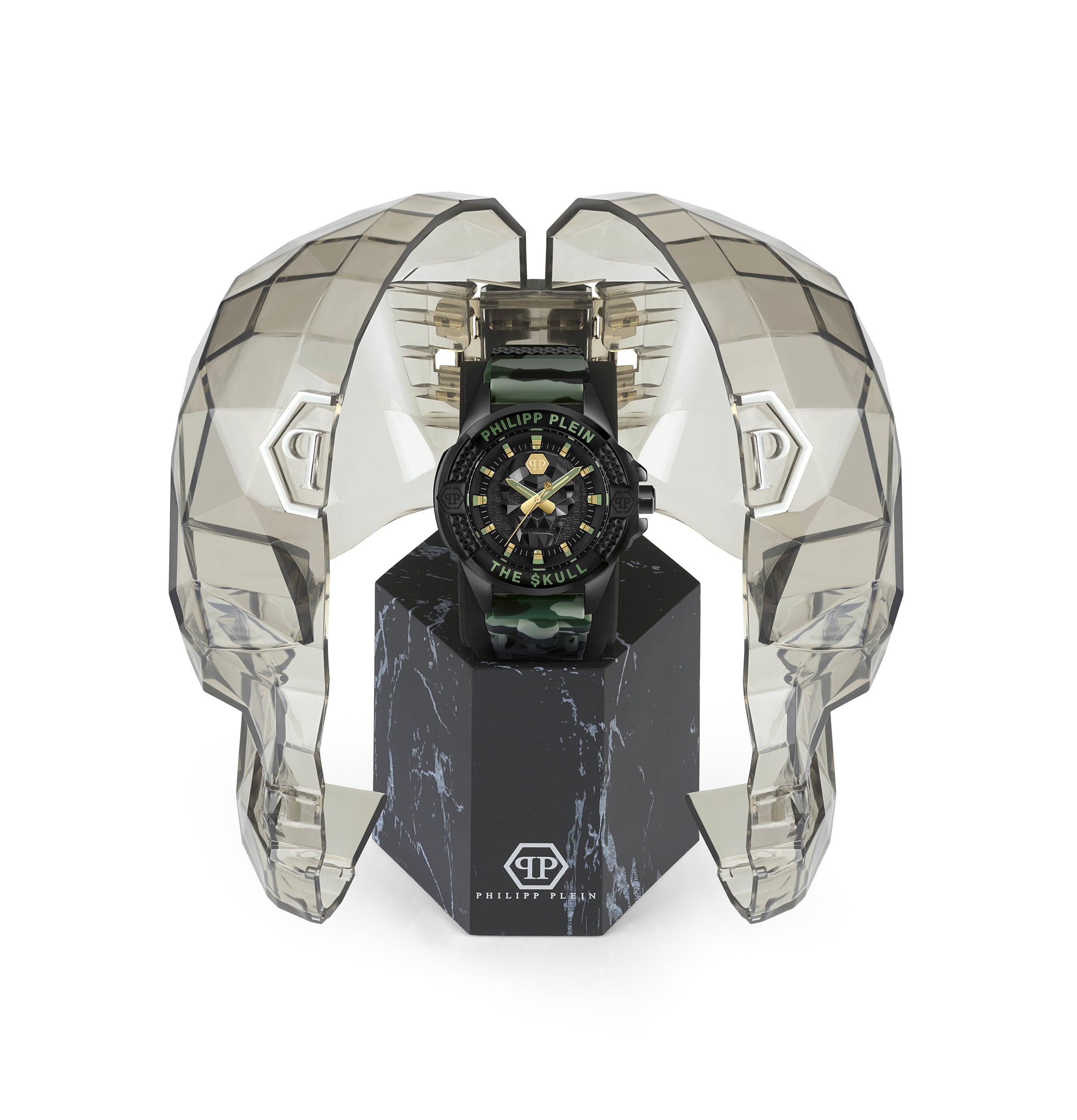 Die Philipp Plein Armbanduhr - The Camouflage $kull präsentiert sich in einem transparenten, eckigen Gehäuse in Form eines Totenkopfes auf einem schwarzen Ständer.