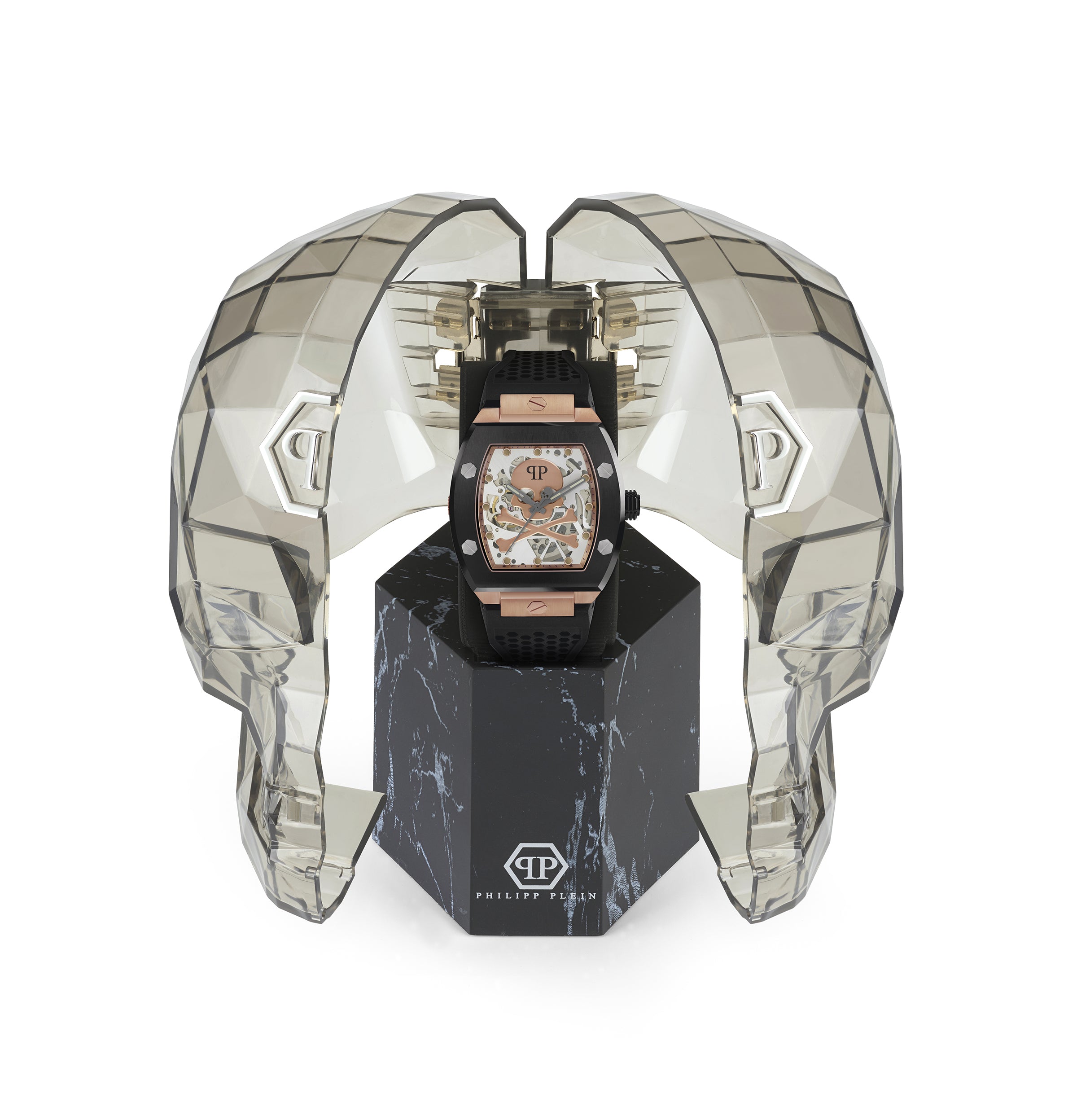 Die Philipp Plein Armbanduhr - The $keleton wird in einem transparenten, geometrischen Gehäuse in Form eines Totenkopfes auf schwarzem Marmor präsentiert und spiegelt die kühne Essenz der Skeleton-Kollektion von Philipp Plein wider.
