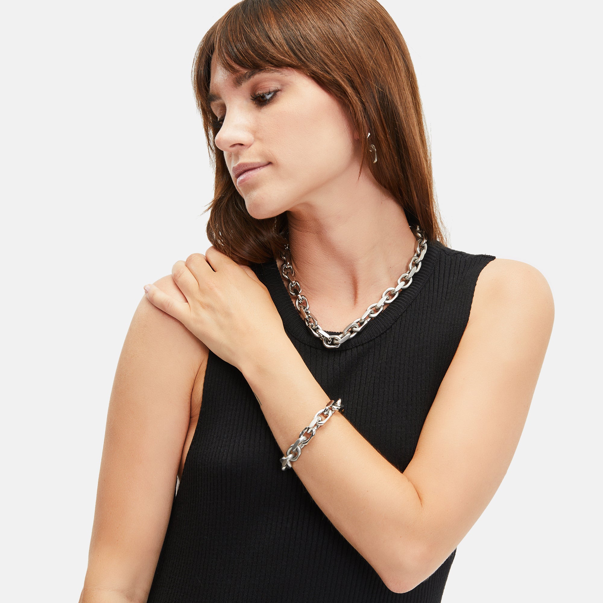Frau in einem ärmellosen schwarzen Oberteil mit der Tamaris Halskette - Matt and Shiny und Armband, mit Blick zur Seite.