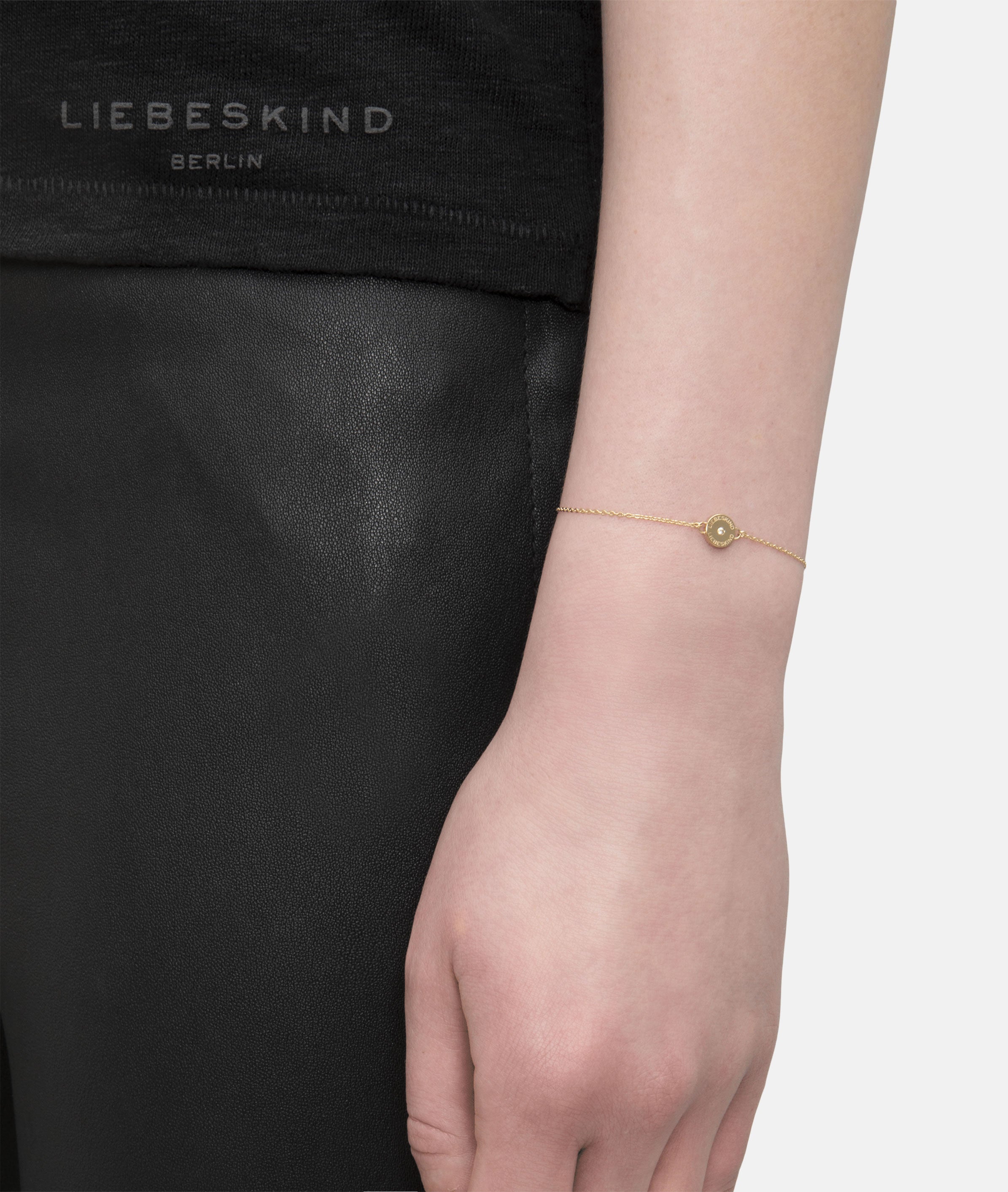 Liebeskind Berlin Armband bestehend aus einer filigranen, goldenen Kette mit einem Anhänger mit Logoaufdruck und einem zentrierten Zirkoniastein; Tragebild