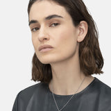 Liebeskind Berlin Halskette bestehend aus einer silbernen Gliederkette mit kleinen Details entlang der Kette und Plättchenanhänger mit Logogravur; Tragebild