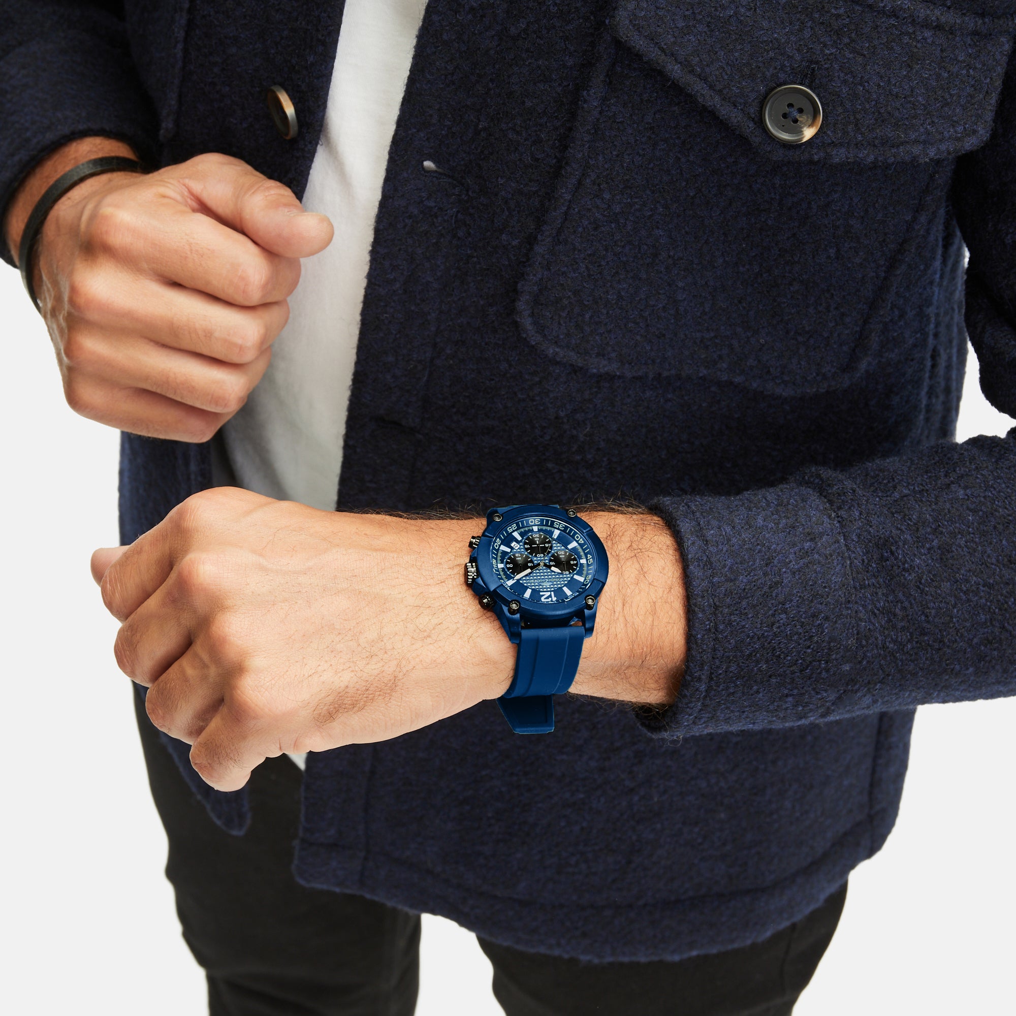 Eine Person, die die Fynch-Hatton Armbanduhr - The Blue Chrono und eine marineblaue Jacke trägt, steht mit einer Hand an ihrem Ärmel.