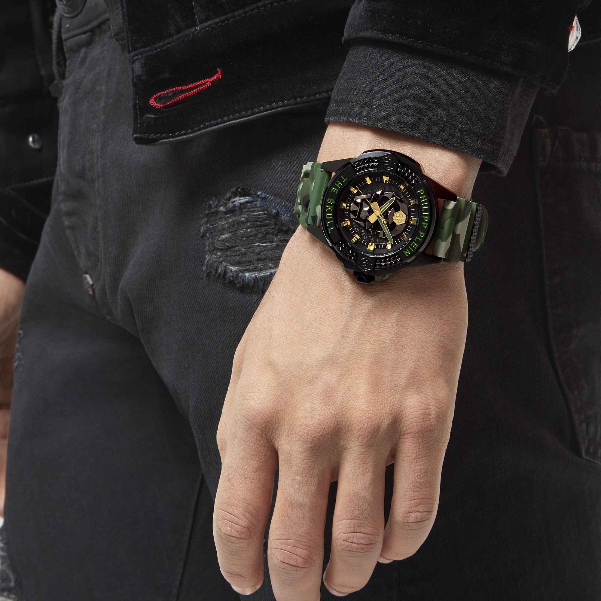 Philipp Plein Armbanduhr mit schwarzem Zifferblatt mit schwarzem Totenkopfdesign und gelben sowie grünen Akzenten, schwarzem Gehäuse und camouflagefarbenem Edelstahlband Tragebild