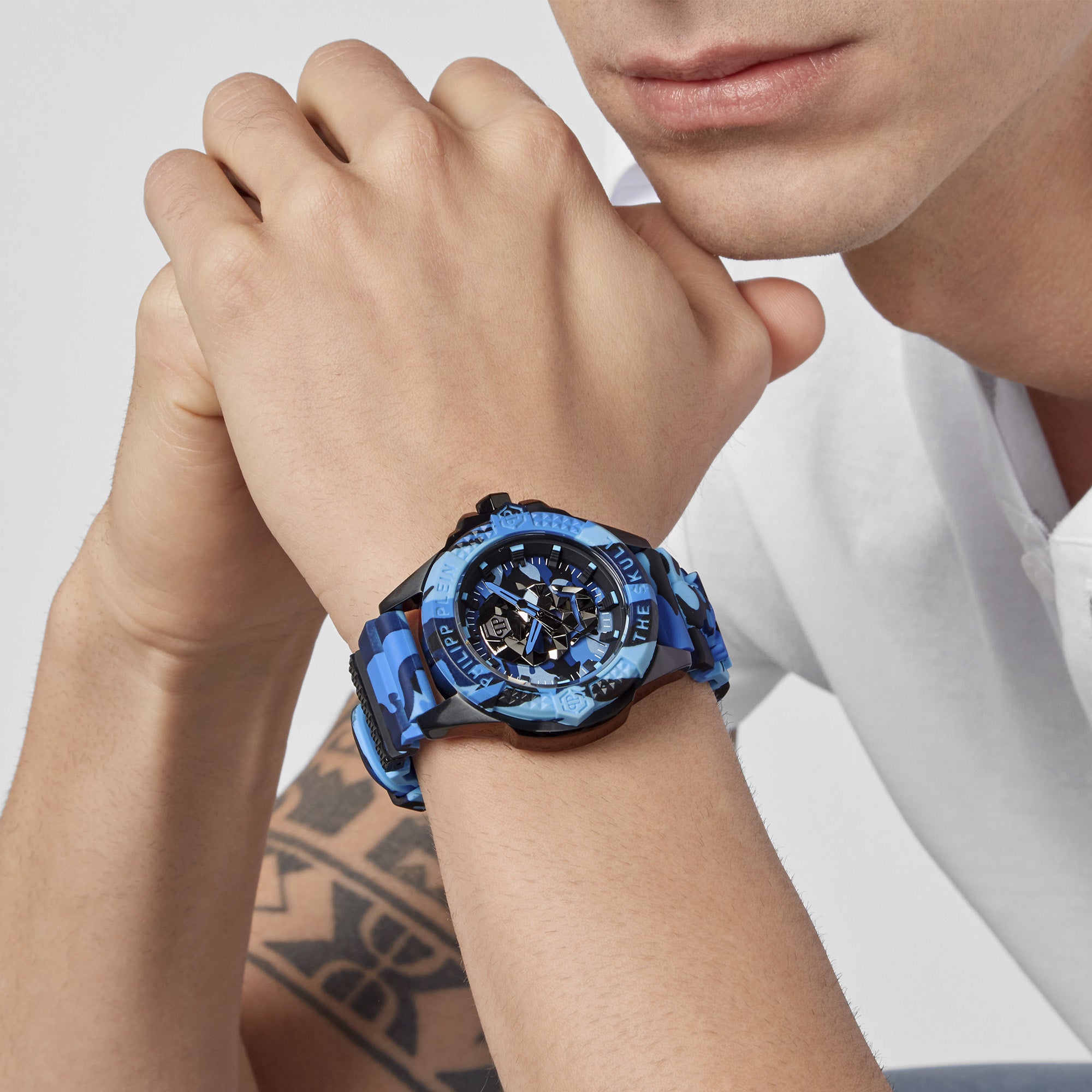 Philipp Plein Armbanduhr mit blau-camouflagenfarbenem Zifferblatt mit schwarzem Totenkopfdesign und schwarzen sowie blauen Akzenten, schwarzem Gehäuse mit blau-camouflagefarbenem Topring und blau-camouflagefarbenem Edelstahlband Tragebild