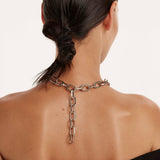 Eine Frau mit einem gedrehten Dutt trägt die The Large Signature Halskette von PDPaola, deren elegante Kette über ihren nackten Rücken fällt.