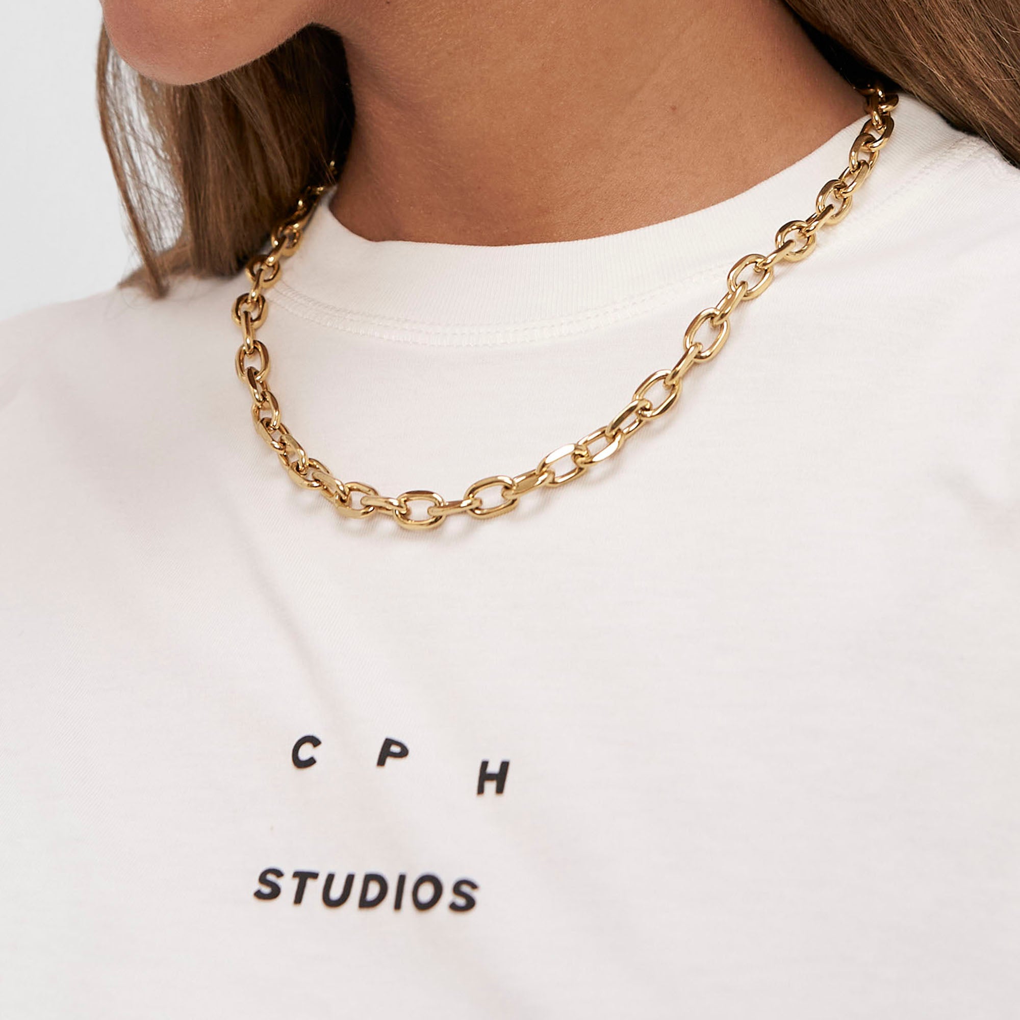 Frau trägt eine klobige Copenhagen Studios Halskette - Basic Chains und ein weißes Shirt mit COPENHAGEN STUDIOS Schriftzug.