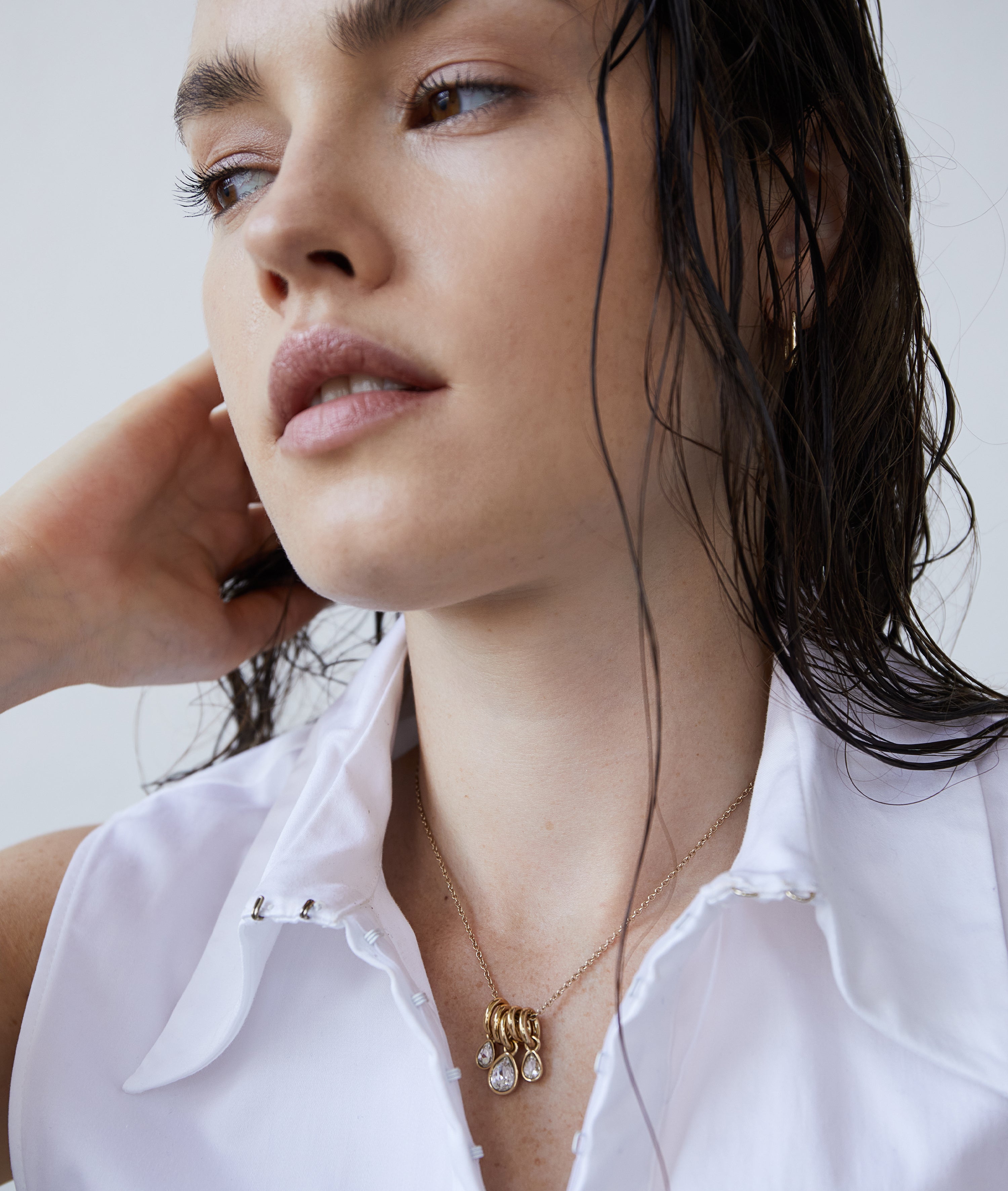 Frau mit nassem Haar, weißem Hemd mit Kragen und einem zeitlosen Accessoire: die Echtzeit Halskette - Like Diamonds by Echtzeit, eine elegante Halskette mit einem stilvollen Tropfenanhänger.
