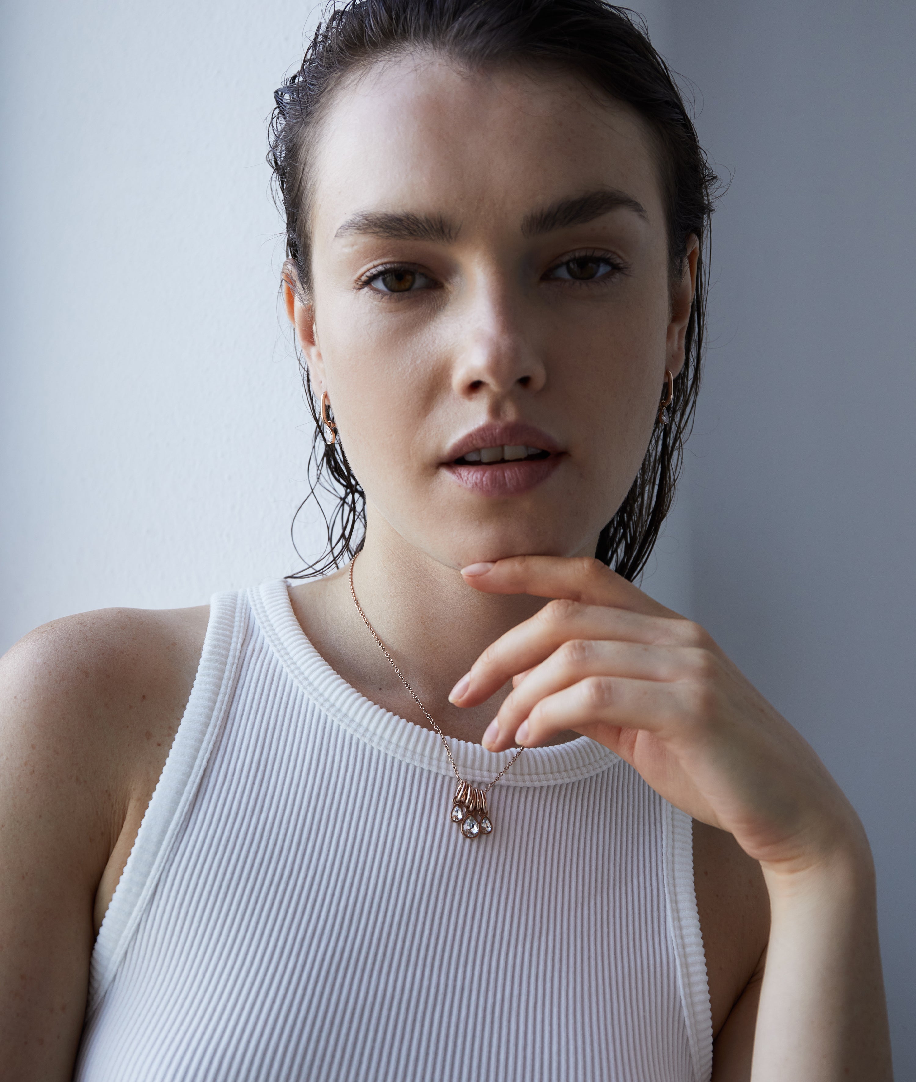 A woman in einem weißen, ärmellosen Top präsentiert die Echtzeit Halskette - Like Diamonds samt passender Ohrringe von Echtzeit - ein zeitloses Accessoire für jeden Anlass.