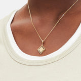Goldener Liebeskind Berlin Charm mit drehbarem Plättchen, graviertem Wassermann-Zodiac-Symbol auf der einen und Logoschriftzug auf der anderen Seite; Tragebild