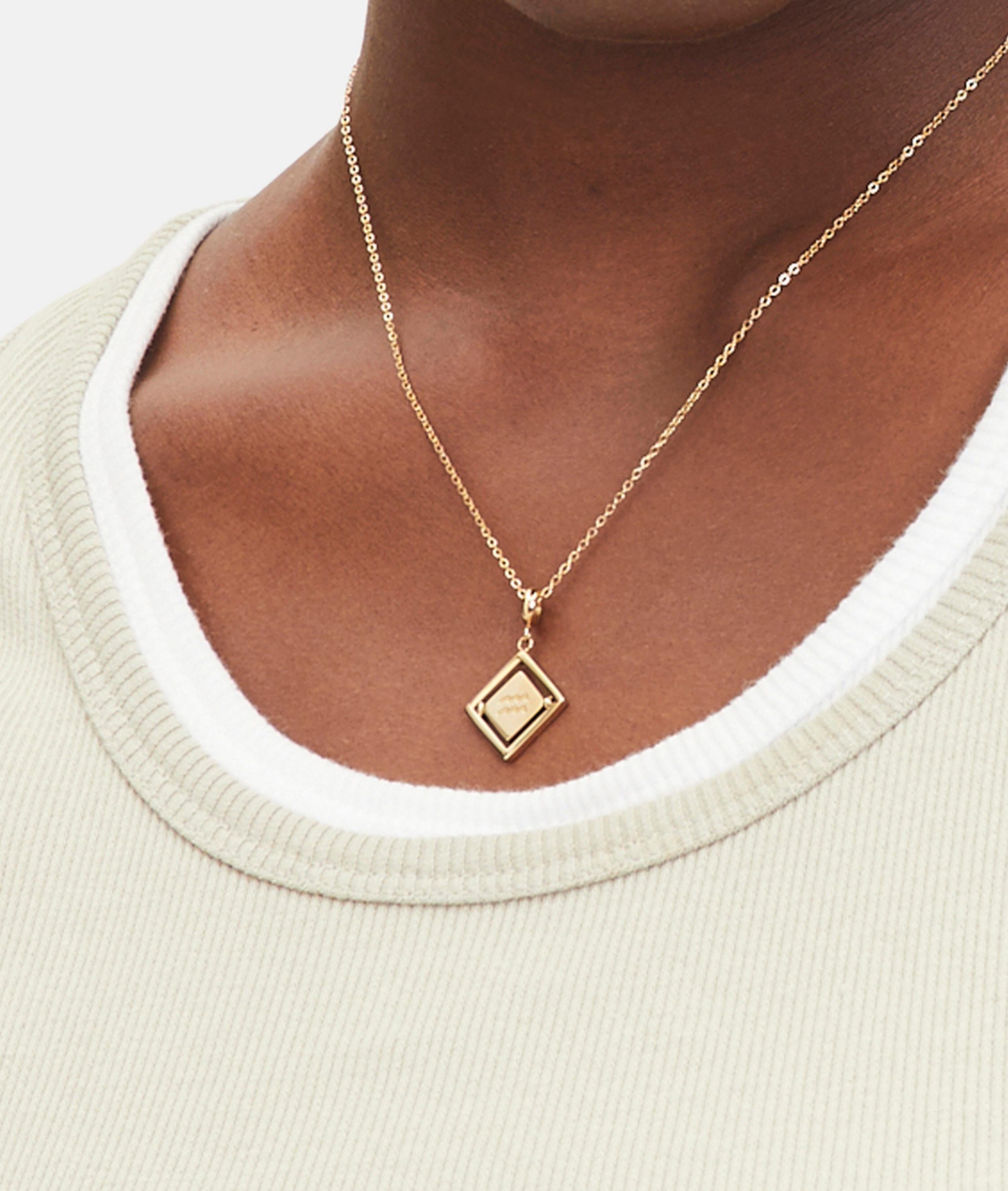 Goldener Liebeskind Berlin Charm mit drehbarem Plättchen, graviertem Wassermann-Zodiac-Symbol auf der einen und Logoschriftzug auf der anderen Seite; Tragebild
