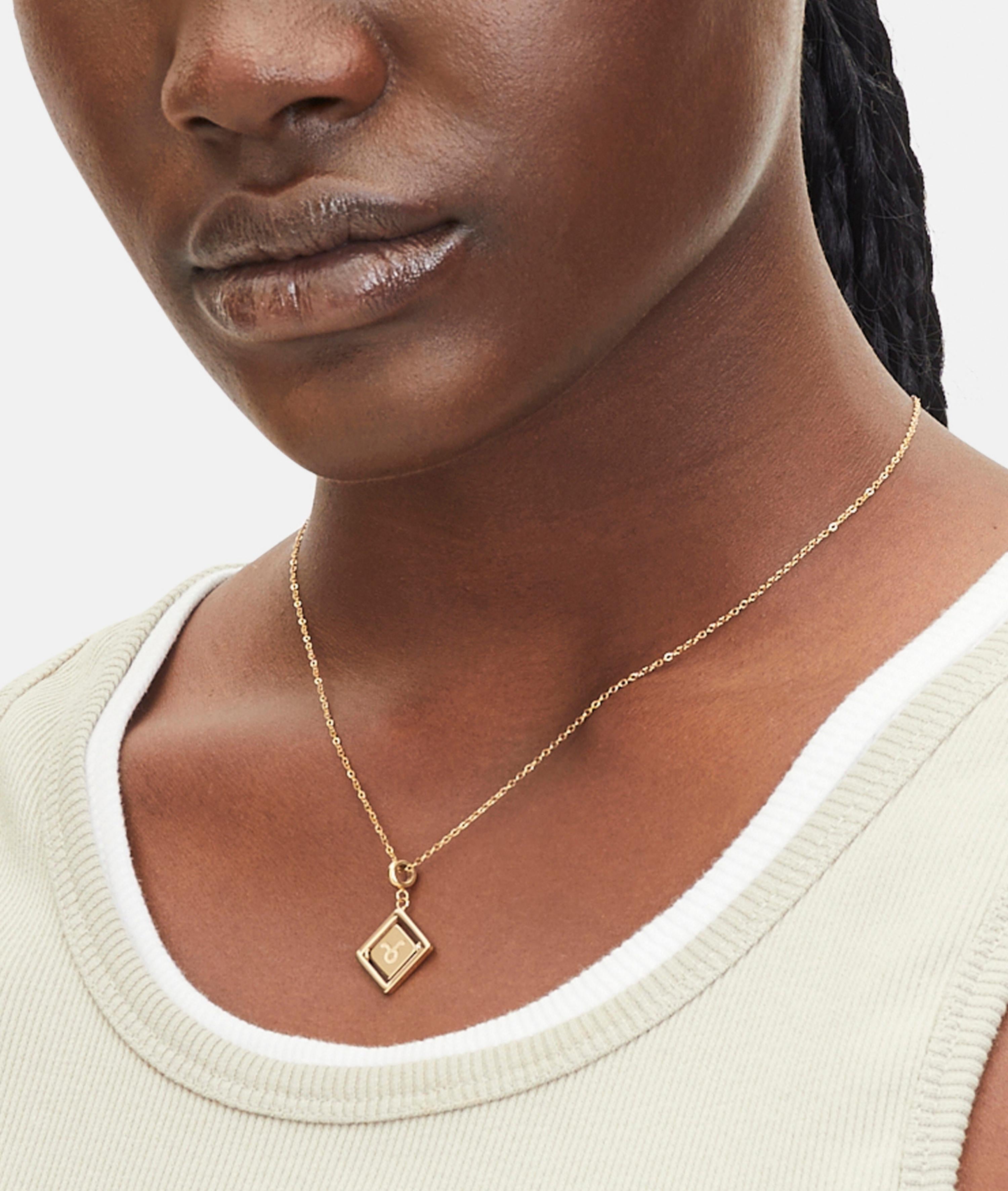 Goldener Liebeskind Berlin Charm mit drehbarem Plättchen, graviertem Stier-Zodiac-Symbol auf der einen und Logoschriftzug auf der anderen Seite; Tragebild