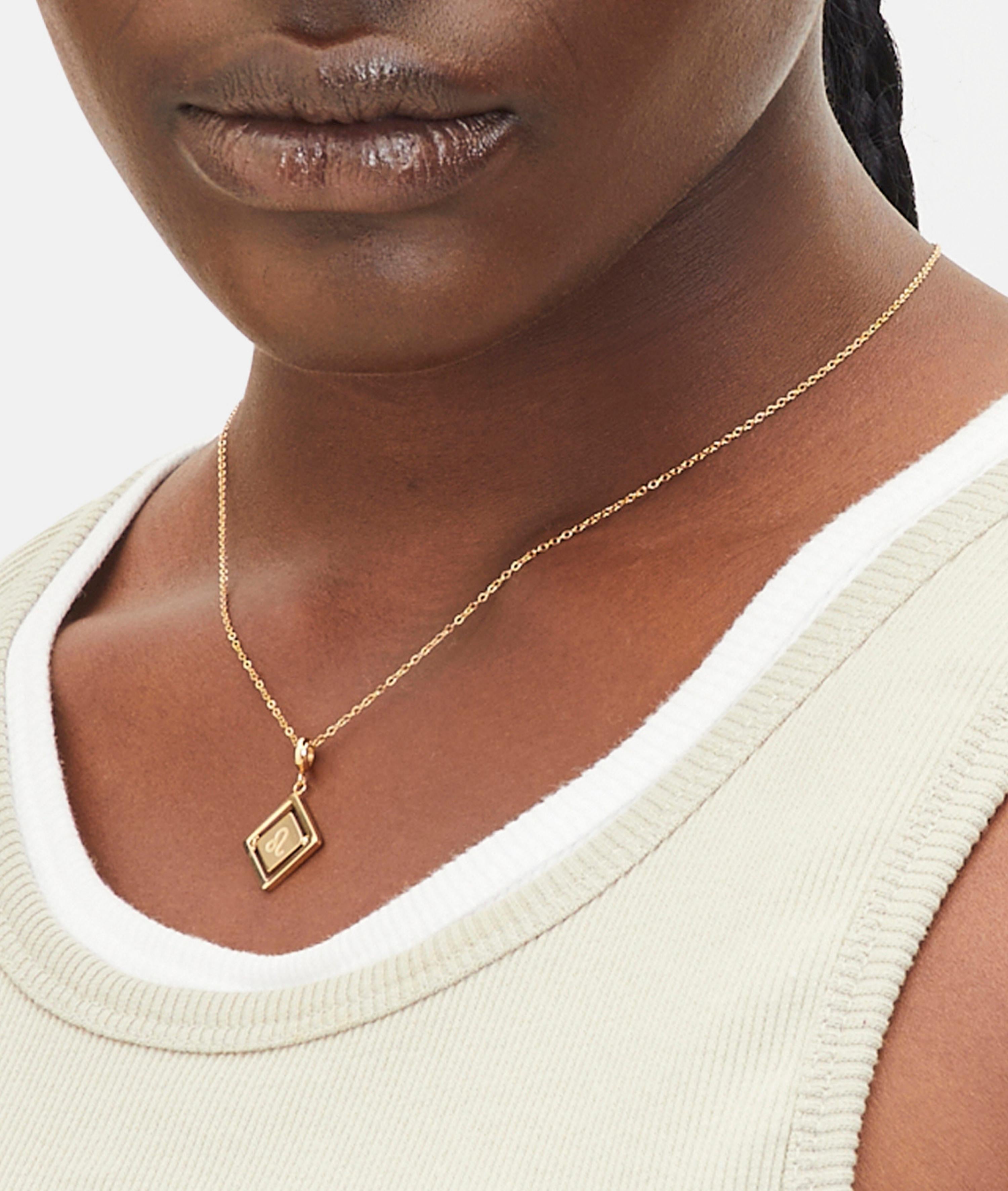 Goldener Liebeskind Berlin Charm mit drehbarem Plättchen, graviertem Löwe-Zodiac-Symbol auf der einen und Logoschriftzug auf der anderen Seite; Tragebild