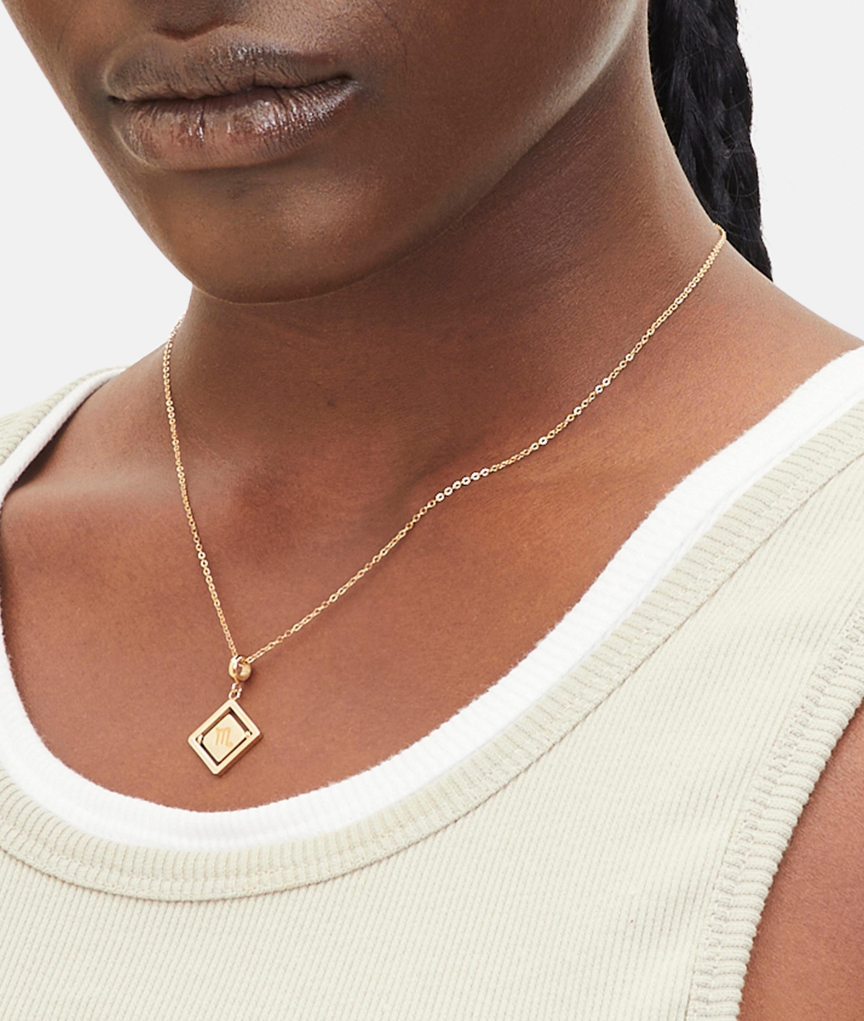 Goldener Liebeskind Berlin Charm mit drehbarem Plättchen, graviertem Skorpion-Zodiac-Symbol auf der einen und Logoschriftzug auf der anderen Seite; Tragebild