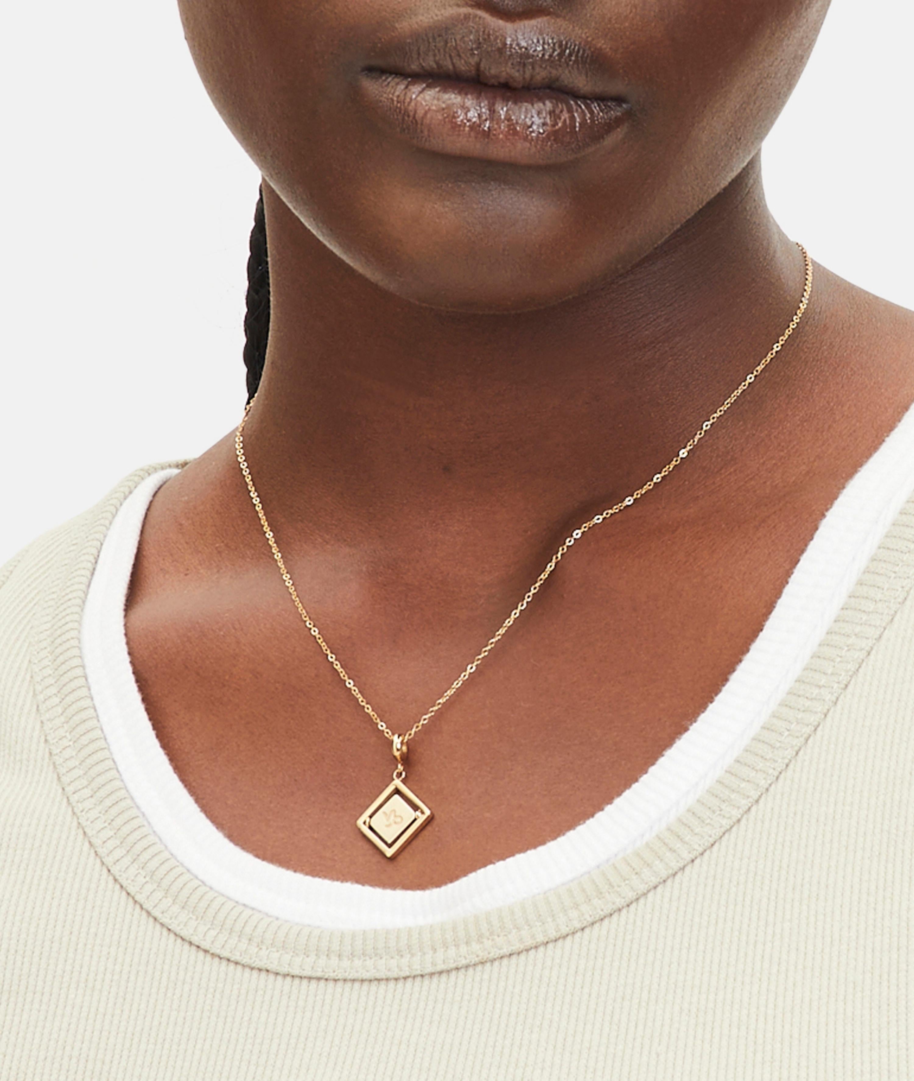 Goldener Liebeskind Berlin Charm mit drehbarem Plättchen, graviertem Steinbock-Zodiac-Symbol auf der einen und Logoschriftzug auf der anderen Seite; Tragebild