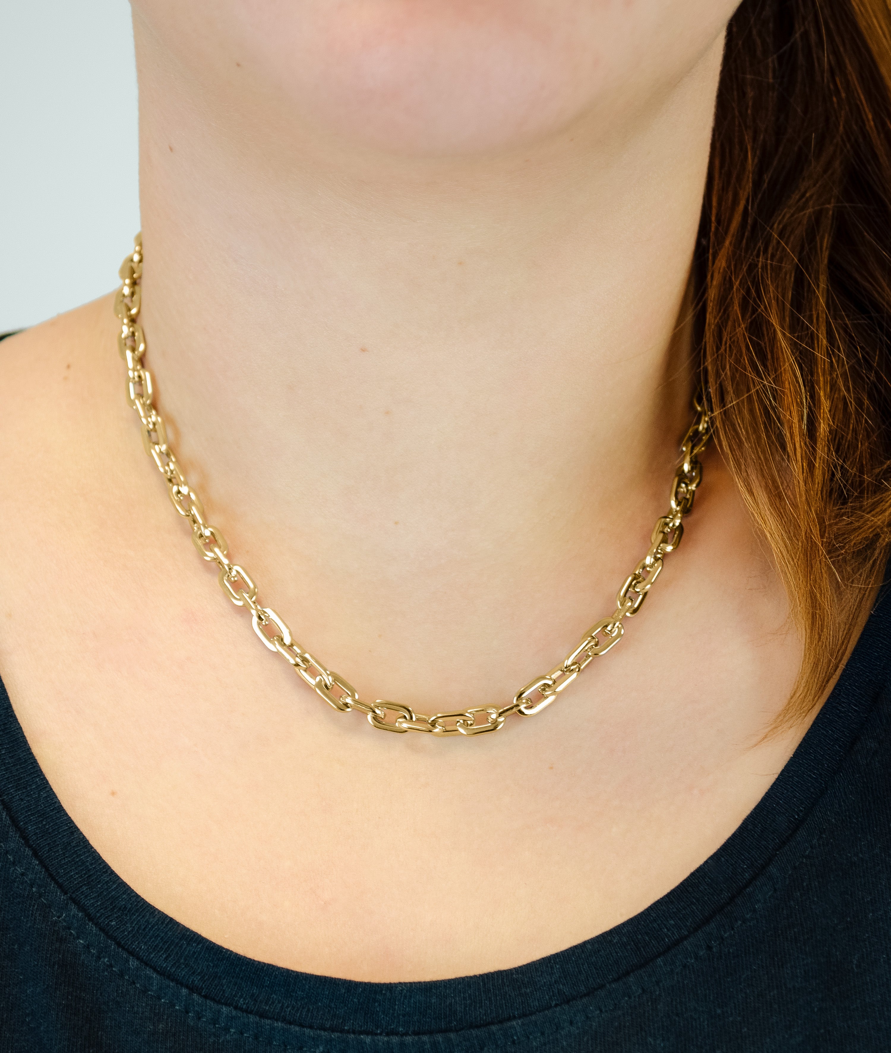 Eine Frau trägt die LIEBESKIND BERLIN Halskette - The Double Tag von Liebeskind Berlin und ein dunkles Oberteil, ihr Haar fällt über eine Schulter, betont eleganten Schmuck.