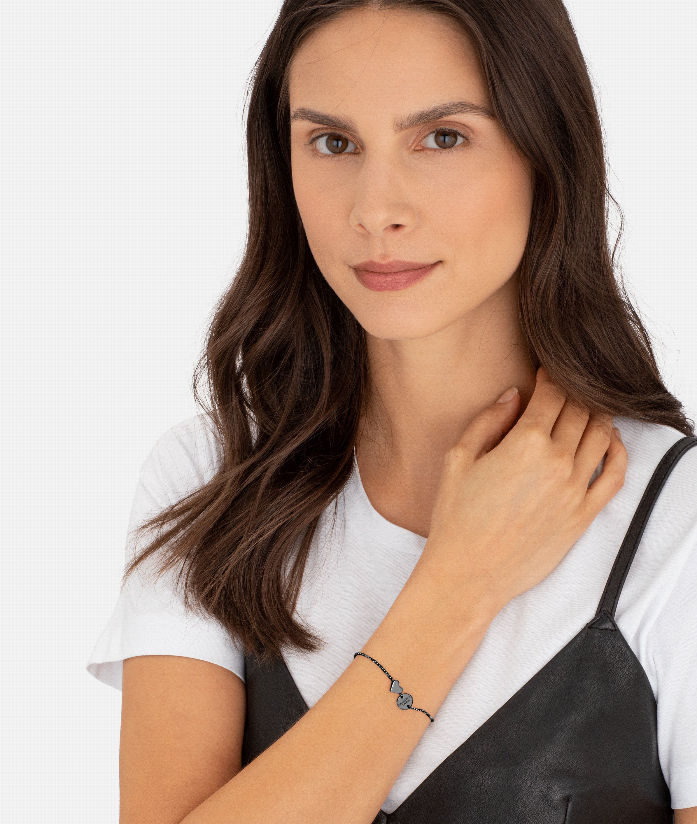 Frau mit langen braunen Haaren trägt ein weißes T-Shirt, ein schwarzes Top und das LIEBESKIND BERLIN Armband - Together, Today, Everyday von Liebeskind Berlin - ein ideales Geschenk für einen besonderen Menschen.