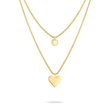 Zwei goldene LIEBESKIND BERLIN Halsketten von Liebeskind Berlin, eine mit rundem Anhänger und eine mit Herzanhänger aus hochwertigem Edelstahl auf weißem Hintergrund.