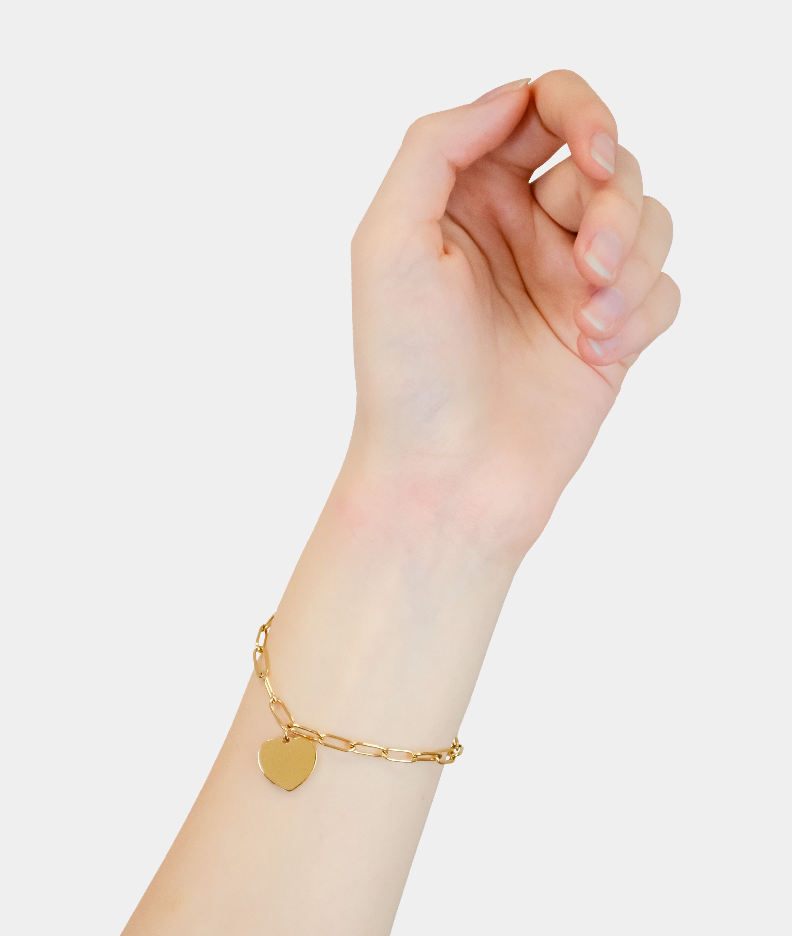 Eine Hand trägt das Liebeskind Berlin Armband - My Heart mit einem goldenen herzförmigen Anhänger auf weißem Hintergrund.