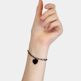 Eine Hand trägt das LIEBESKIND BERLIN Armband - My Heart von Liebeskind Berlin mit einem Herzanhänger vor einem schlichten hellen Hintergrund.