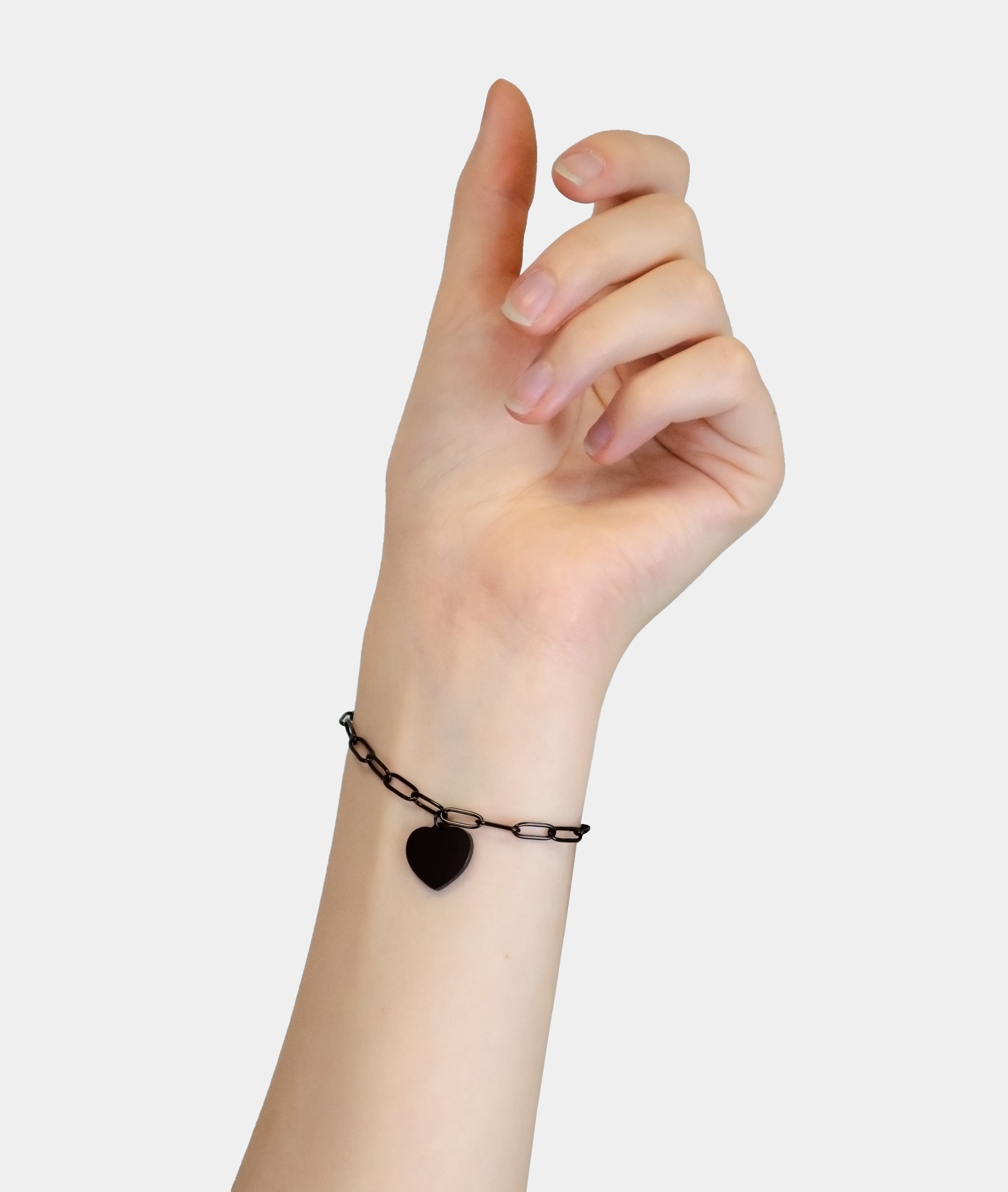 Eine Hand trägt das LIEBESKIND BERLIN Armband - My Heart von Liebeskind Berlin mit einem Herzanhänger vor einem schlichten hellen Hintergrund.