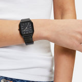 Eine Person trägt eine Liebeskind Berlin Armbanduhr - The Basic Staple, ein weißes Tanktop und eine blaue Jeans mit silbernen Knöpfen.