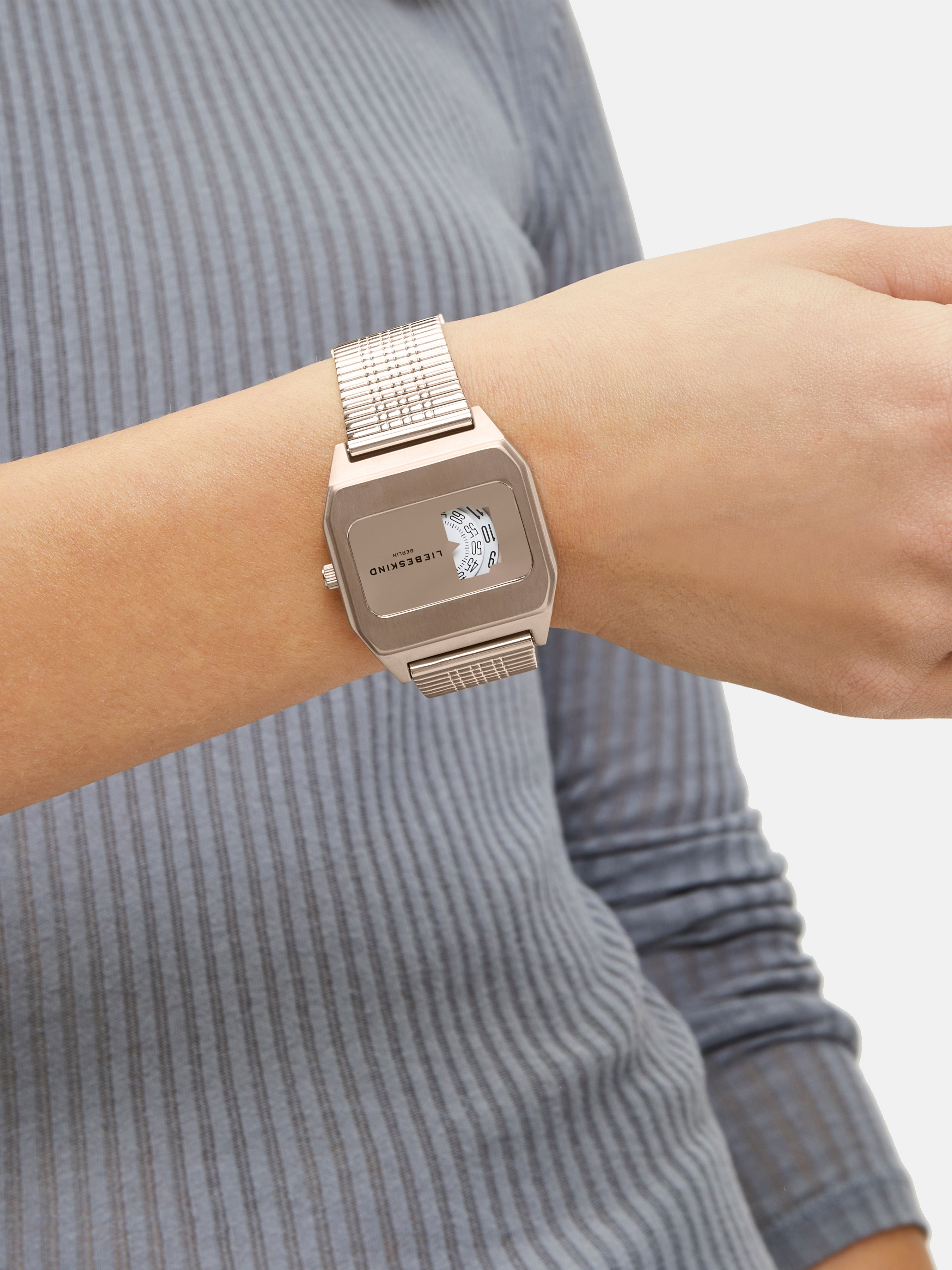 Eine Person in einem blauen gerippten Langarmhemd ergänzt ihren Stil mit der Liebeskind Berlin Armbanduhr - Vinyl Vision, die ein elegantes silbernes Design aufweist.