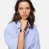 Frau in hellblauem Hemd mit Liebeskind Berlin Armbanduhr - Round Vinyl Vision, schaut mit neutralem Blick in die Kamera.