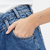 Eine Hand in einer Jeanstasche trägt das Tamaris Armband - The Love Heart mit einem weißen Hemd.
