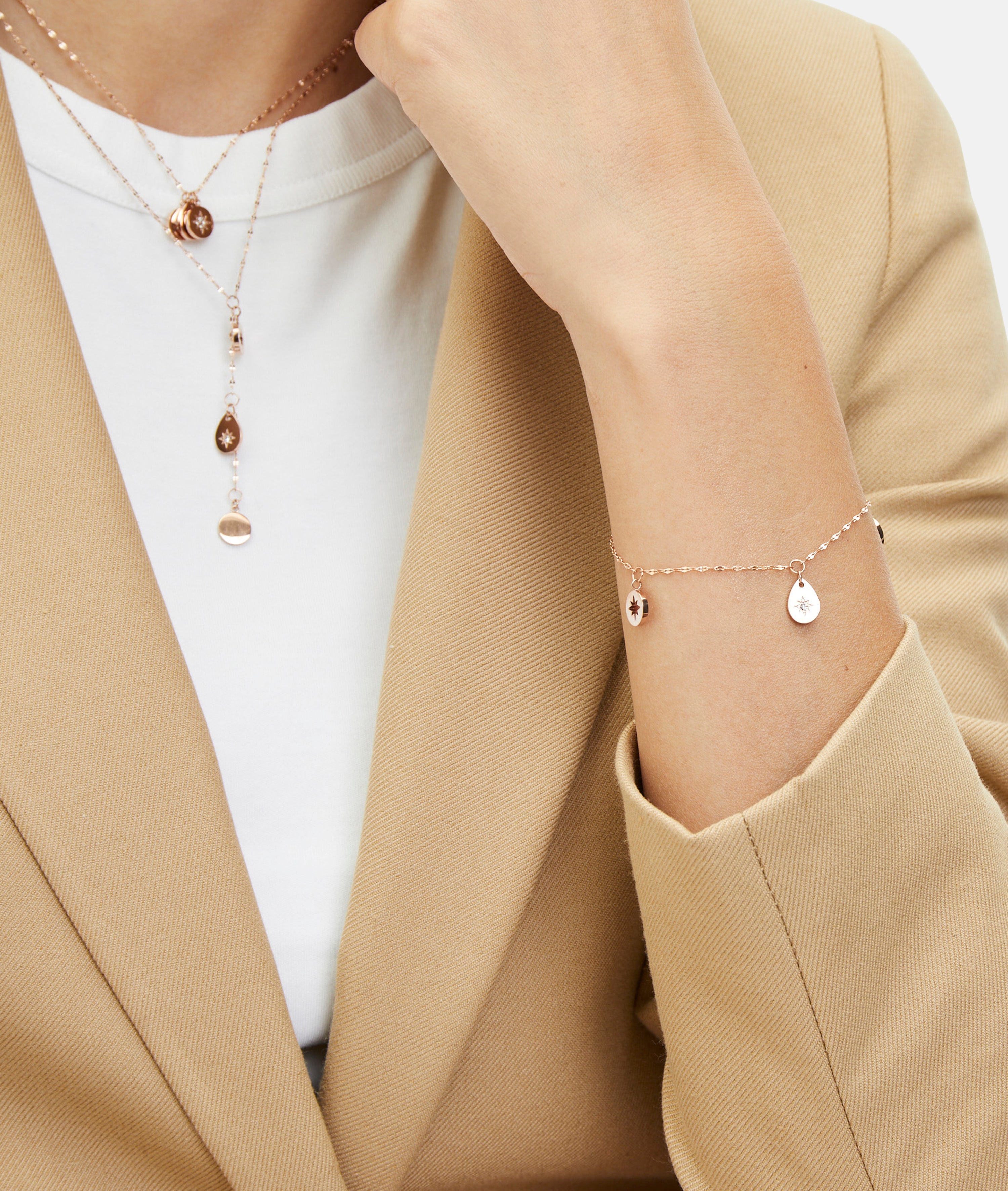Eine Person trägt einen beigen Blazer und Goldschmuck, darunter eine Tamaris-Halskette und das Tamaris-Armband - The Sparkling Stars mit Anhängern.