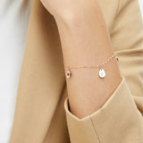 Nahaufnahme eines Handgelenks mit dem Tamaris Armband - The Sparkling Stars: ein goldenes Armband von Tamaris mit zwei kleinen gravierten Anhängern.