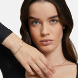 Eine Frau mit langen braunen Haaren trägt das Tamaris Armband - The Flower Pearl von Tamaris, gepaart mit Perlenohrringen und einer floralen Halskette mit Glasperlenanhänger, und posiert anmutig.