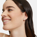 Eine Frau mit glattem braunem Haar und natürlichem Make-up lächelt, während sie Tamaris Ohrstecker - The Flower Pearl, einen floralen Ohrring von Tamaris, trägt.