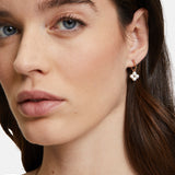 Nahaufnahme einer Frau mit braunen Haaren und natürlichem Make-up, die den Ohrring Tamaris Creole - The Flower Pearl von Tamaris mit floralem Muster trägt, gepaart mit einer dezenten Halskette.