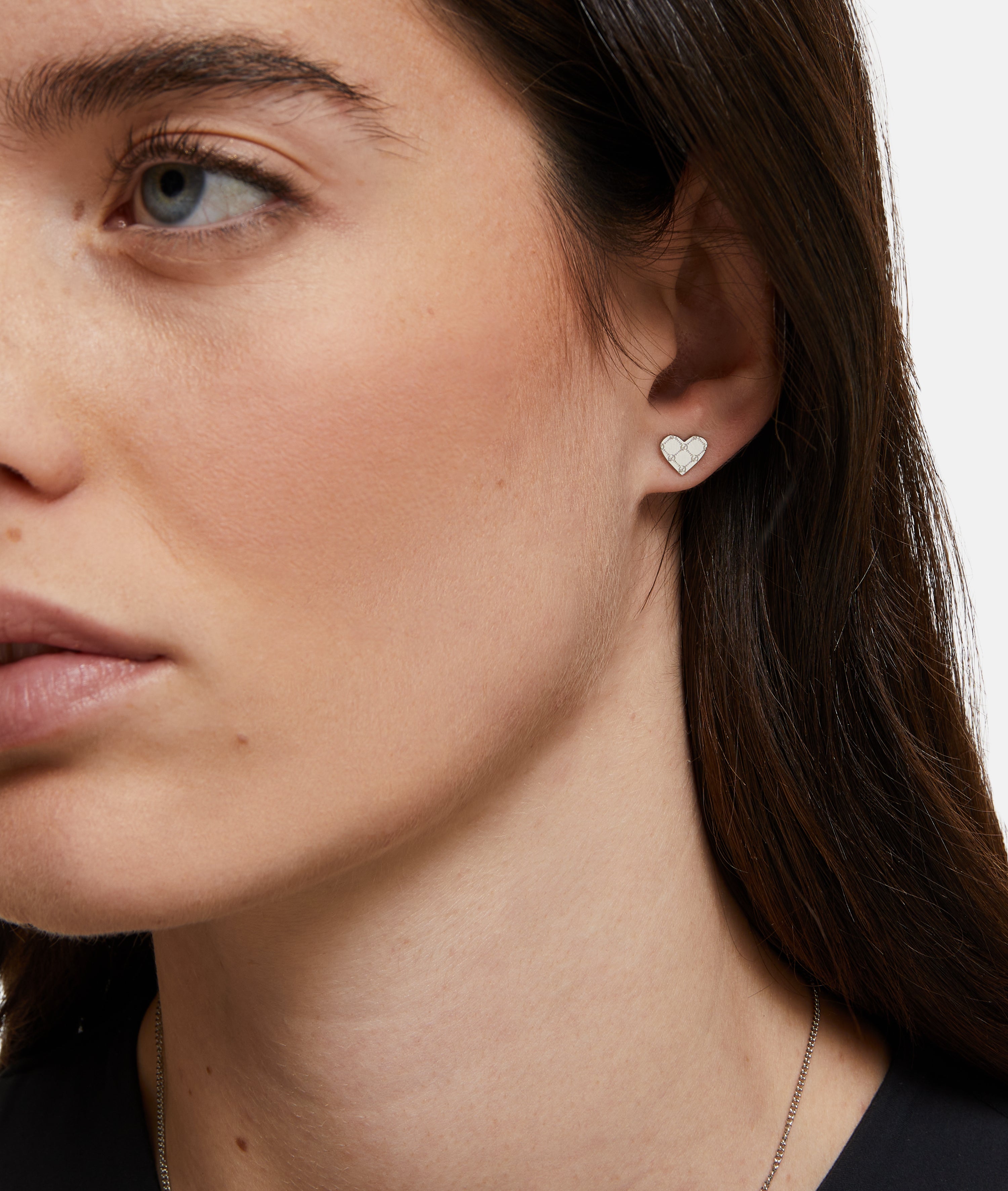 Nahaufnahme einer Frau, die den kleinen, silbernen Tamaris Ohrstecker - The T-Pattern Heart in ihrem linken Ohr trägt - ein elegantes Accessoire von Tamaris und ein perfektes Geschenk für einen besonderen Menschen.