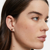 Eine Frau mit heller Haut und braunem Haar trägt Tamaris Ohrstecker - The T-Pattern Heart: kleine, goldene Ohrringe von Tamaris - perfekt als Geschenk.