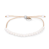 Das Tamaris Armband - The Pearl Beads von Tamaris zeigt eine goldene Kette, weiße Perlen, zarte Glitzerfäden und einen verstellbaren Verschluss auf weißem Hintergrund.