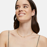 Eine Frau mit langen braunen Haaren lächelt, sie trägt ein graues Spaghettiträgertop und die Tamaris Halskette aus der Silver Collection von Tamaris.