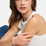 Frau in weißem Tanktop und Jeans trägt das Armband Tamaris - All About Beads und schaut mit neutralem Blick in die Kamera.
