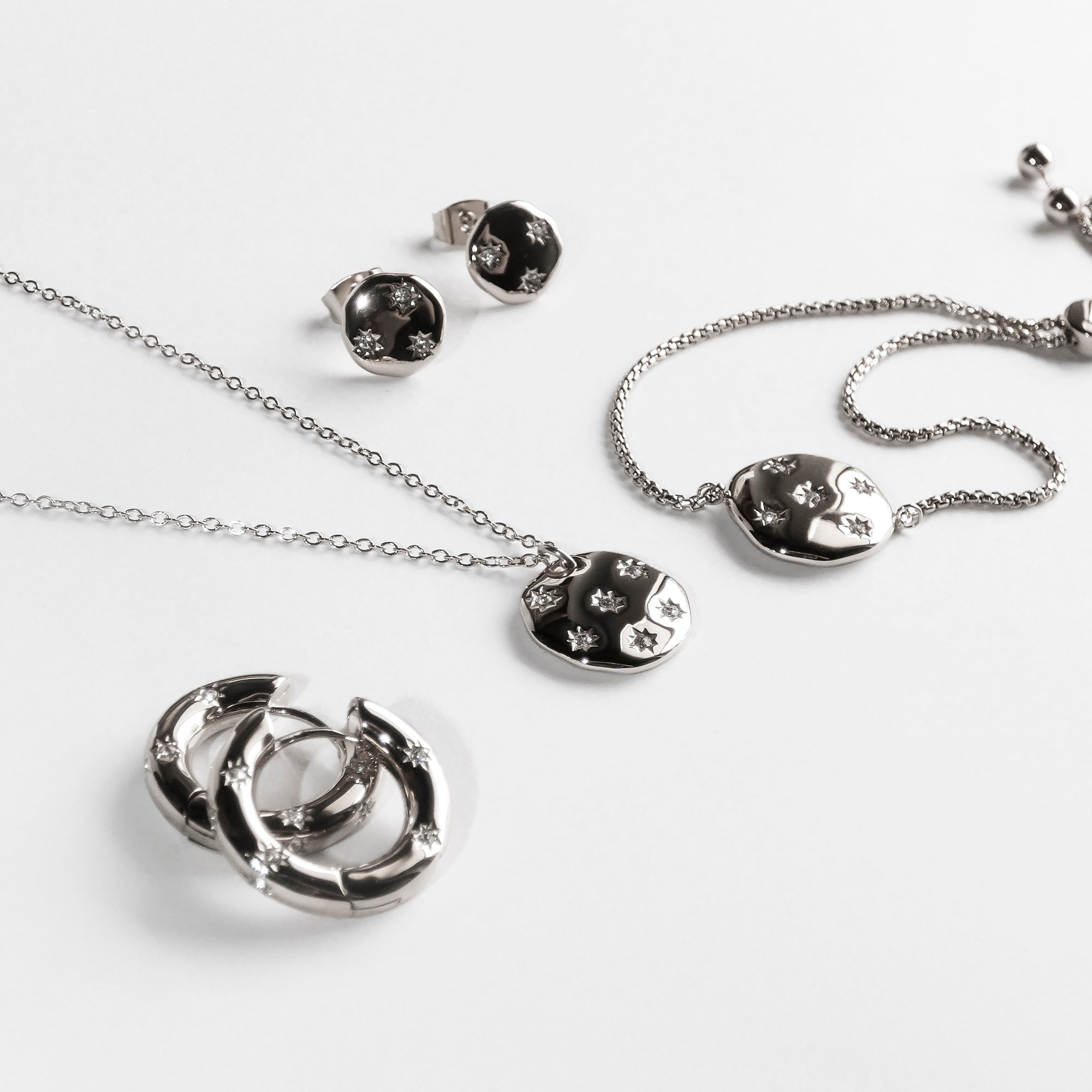 Das Tamaris Halskette - Little Twinkle Schmuckset von Tamaris besteht aus Ohrringen, einer Damen-Halskette und einem Armband mit Stern-Akzenten und funkelnden Zirkoniasteinen, dargestellt auf weißem Hintergrund.