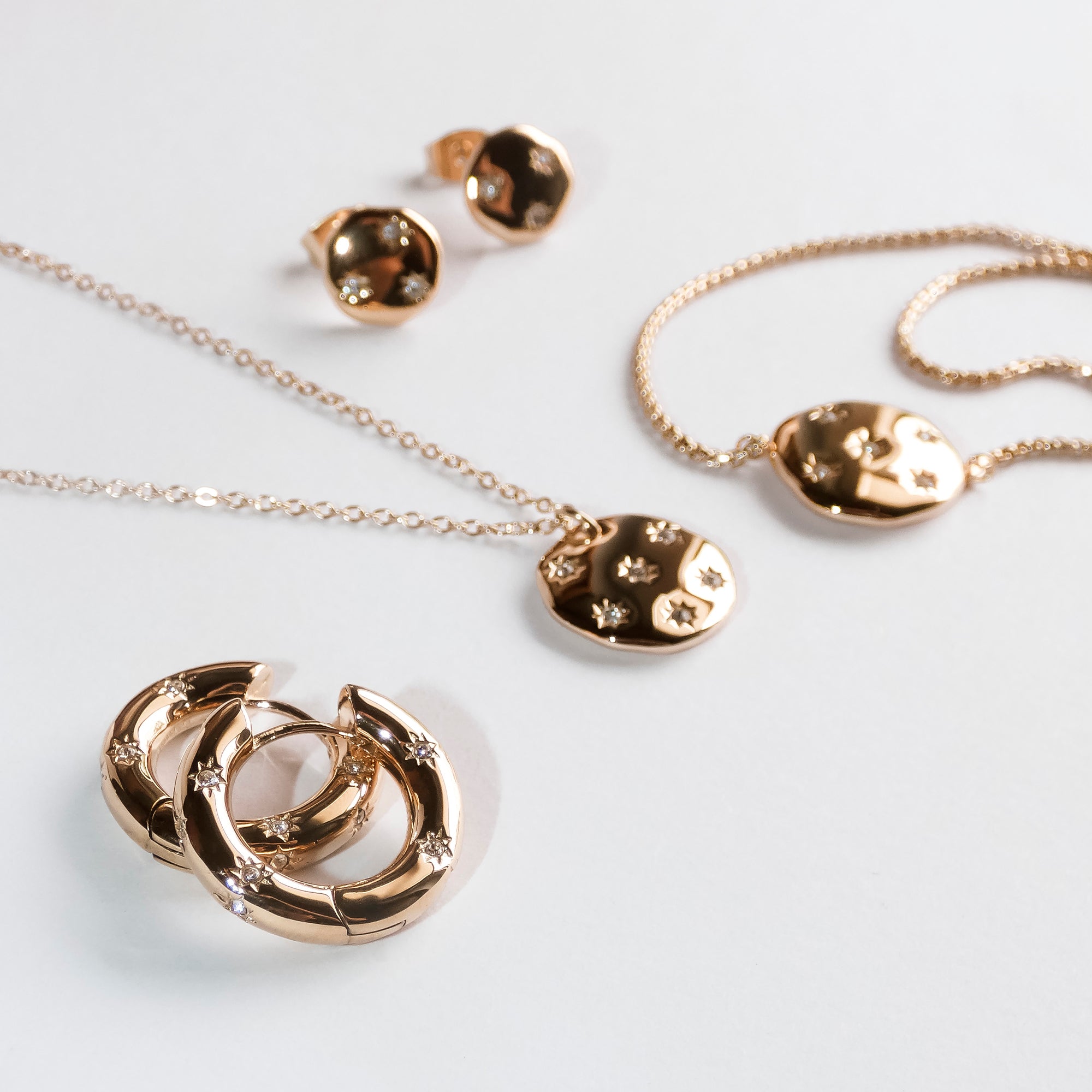 Das Schmuckset Tamaris Creole - Little Twinkle von Tamaris bietet Mond- und Sterndesigns mit Zirkoniasteinen, darunter elegante Ohrringe, Halsketten und Ringe, die alle auf weißem Hintergrund präsentiert werden.