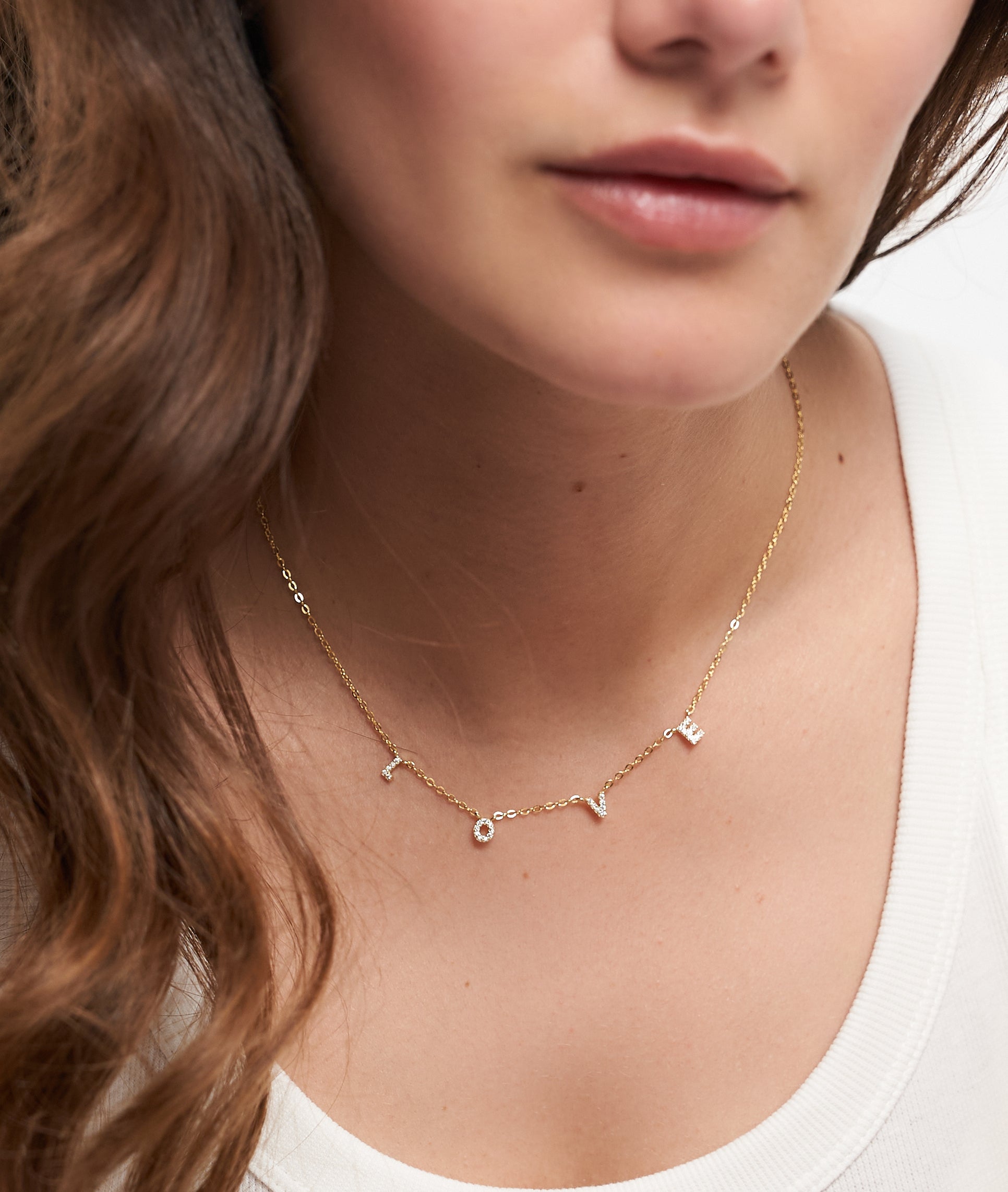 Eine Frau trägt die Tamaris Halskette aus der Silver Love Collection mit LOVE Anhänger und funkelnden Zirkoniasteinen, kombiniert mit einem schlichten weißen Top.