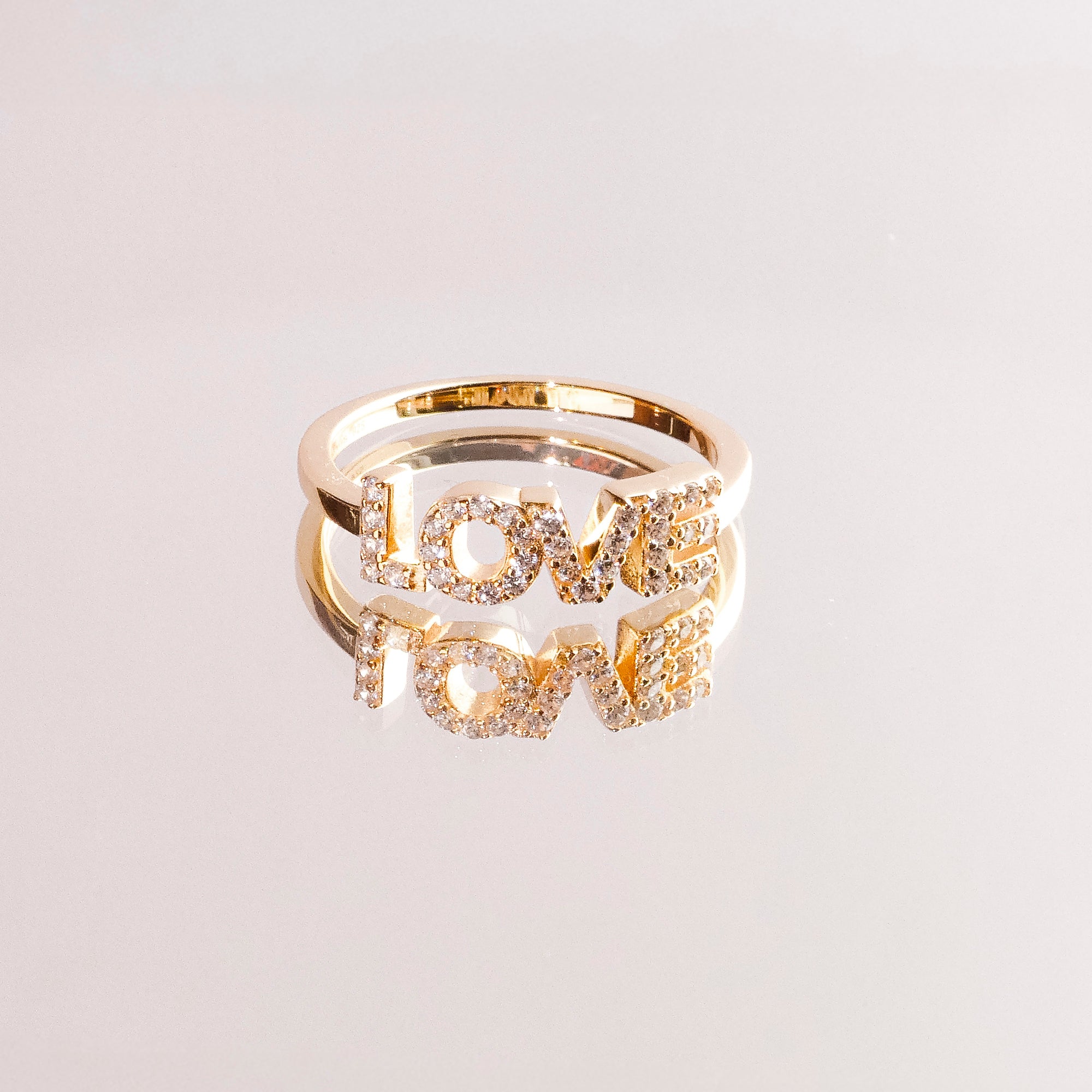 Der Tamaris Ring aus der Silver Love Collection ist mit einem LOVE Schriftzug versehen, der mit funkelnden Zirkonia verziert ist und sich auf einer glänzenden Oberfläche spiegelt.