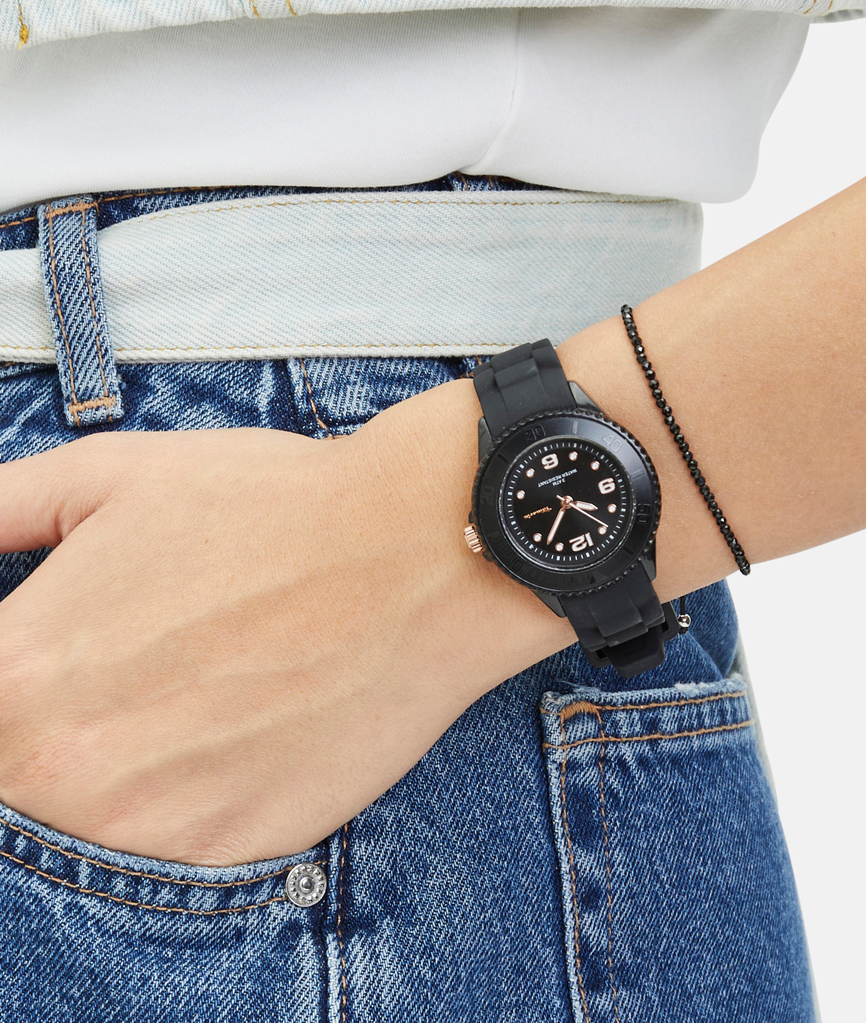 Eine Hand in Blue Jeans mit einer Tamaris Armbanduhr - The Black Silicone, einer sportlichen schwarzen Uhr mit dünnem Silikonband, am Handgelenk.